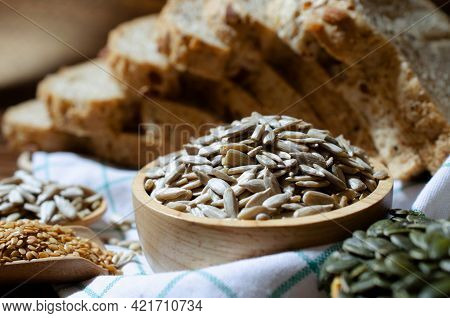 Closed Up Organic Sunflower Seeds In Wooden Bowl Over Blur Wholewheat Bread, Golden Flax And Pumpkin