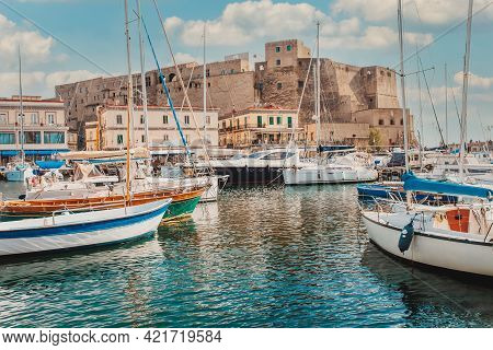 Castel Dell\\\'ovo Or Egg Castle a medieval fortress located in the Gulf of Naples. Famous historical mediterranean coast fortress port. Colorful buildings, yachts and boats, embankment and gulf of Naples