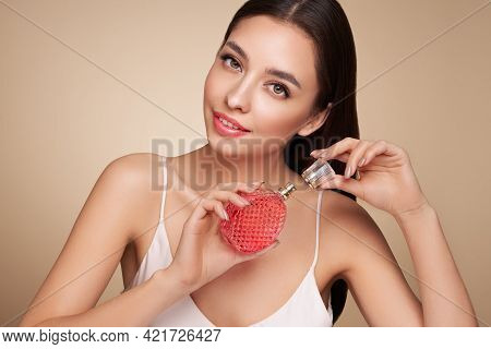 Young Beautiful Woman With A Bottle Of Perfume. Model With Healthy Skin, Close Up Portrait. Cosmetol