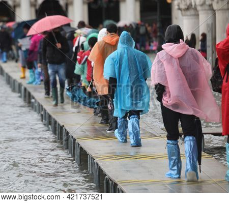 Many People Walk Over The Elevated Walkway During High Tide In Venice With Gaiters On Their Feet And
