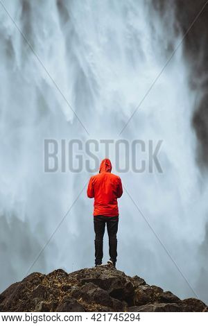 Man in a red windbreaker at the Haifoss waterfall, Iceland