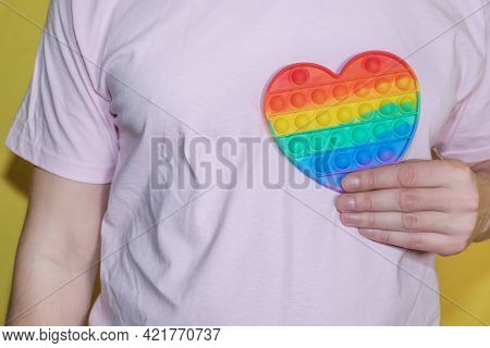 Man Holding Rainbow Heart In His Hand. Lgbt Or Glbt Concept. Pop Fidget Sensory Toy For Autism Speci