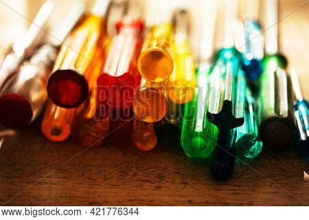 Tools of the trade. Many kinds of screw drivers with colorful grips on a work bench, with incoming window light.