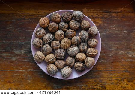 A Handful Of Walnuts On A Pink Plate
