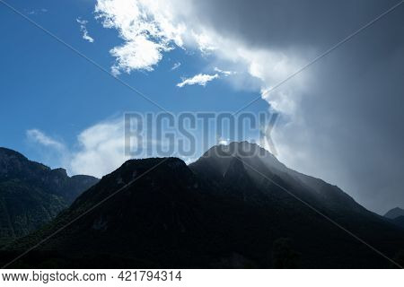 Atmosphere Shortly After A Thunderstorm. Blue Sky And Dark Clouds Around A Hill