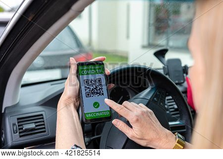 Driver In Car Shows A Digital Covid-19 Immunity Vaccine Passport, New Normal Travel Concept