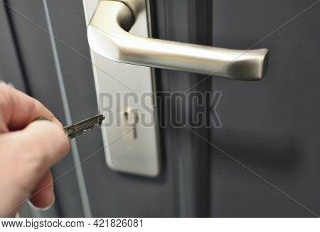 A Hand Holding A Key For Inserting A Key Into The Door Lock. Unlocking The Security Lock.