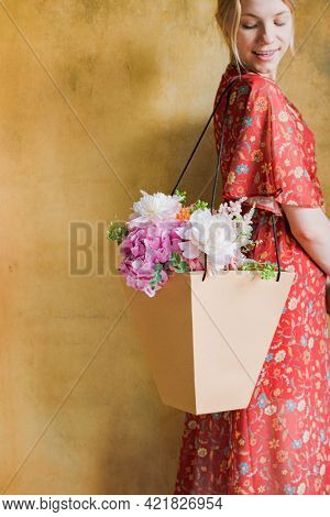 Woman carrying a bouquet of flowers in a paper bag
