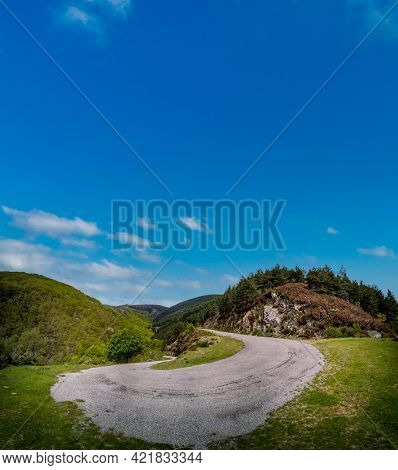 Steep High Slope U-shape Mountain Road Under Blue Sky
