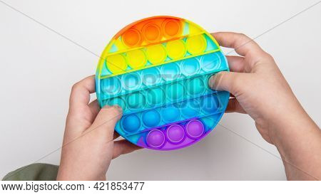 Child playing with the colorful pop It fidget. Close up kid hands playing with the colorful poppit toy in home