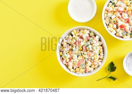 Imitation Crab Salad With Crab Sticks, Corn, Eggs, Cucumber And Rice In Bowls Over Yellow Background