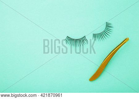Set Of False Eyelashes Extencions On Mint Background With Tweezer. Minimalism. Top View
