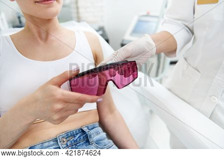 Closeup Of Doctor Aesthetician Hands Bringing Protective Uv Goggles To Client During Visit For Laser