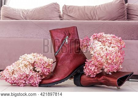 Stylish New Red Leather Women Boots With Low Heels And Fresh Lilac Flowers On Floor Near Pink Couch 