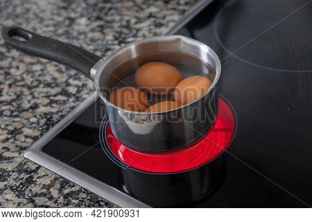 Four Eggs In A Steel Aluminum Pot Are Cooked On An Electric Cooker