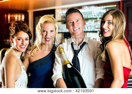 Gode venner - bartender og kvinder - med en stor magnum flaske champagne på bar at have det sjovt