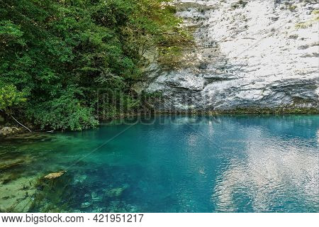 The Lake Is Surrounded By Sheer Cliffs. The Aquamarine Water Is Calm And Clear. Reflection. Stones A