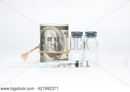 A Picture Of Fake Money, Two Dosses Of Vaccines And Syringe. Lot Of Money Been Spend To The Househol