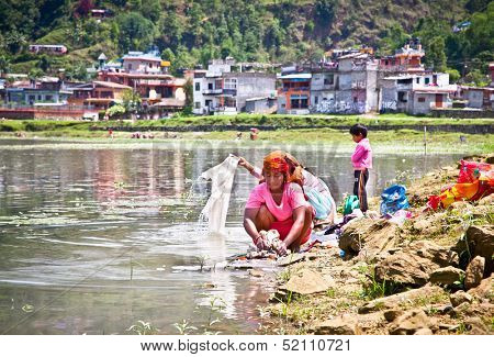 POKHARA,NEPAL-MAY 25:Family washing cloth in Fewa lake on May 25, 2013, Pokhara,Nepal.One of the most beautiful Lakes of Pokhara Valley is the well-known Phewa Lake.