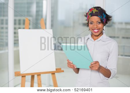 Smiling artistic woman holding sketchpad and looking at camera