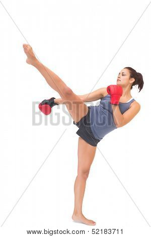 Attractive sporty brunette kick boxing on white background