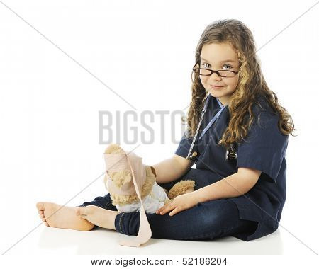 A pretty elementary girl in scrubs looking over her glasses as she bandage's her teddy bear's head.  On a white background.