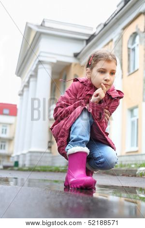 A girl with a thoughtful expression on her face squatted on street