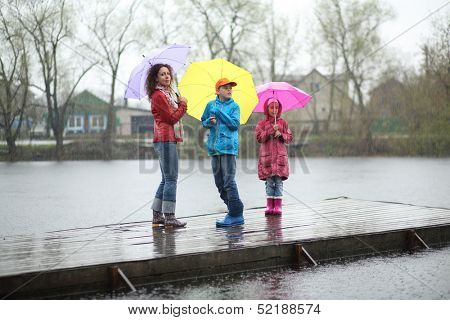 Mother and two children standing in the rain on a wooden pier