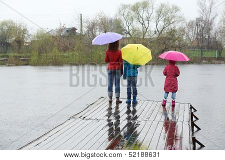 Mother and two kids standing by back at the pier in the rain