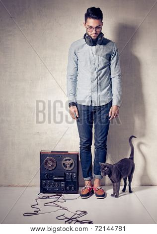 Handsome Man And Cat Listening To Music On A Magnetophone Against Grunge Wall