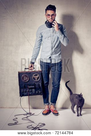 Handsome Man And Cat Listening To Music On A Magnetophone Against Grunge Wall