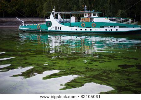 River's ship moored near the river bank in green water