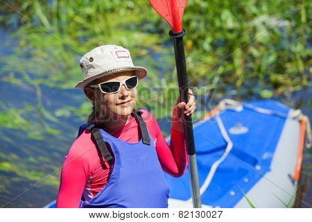 Girl near a kayak on the river