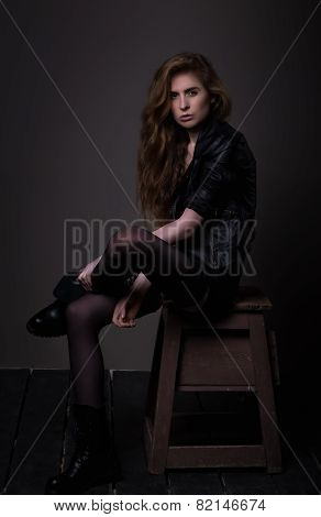 Sitting Attractive Woman In Black Dress And Leather Jacket
