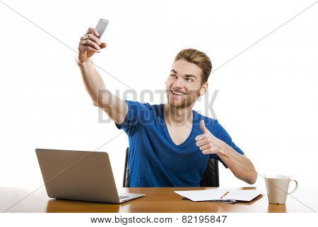 Good looking young man working in the office and taking a selfie 