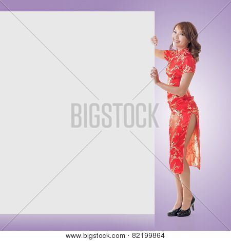 Attractive Chinese woman dress traditional cheongsam and hold blank board, full length portrait.