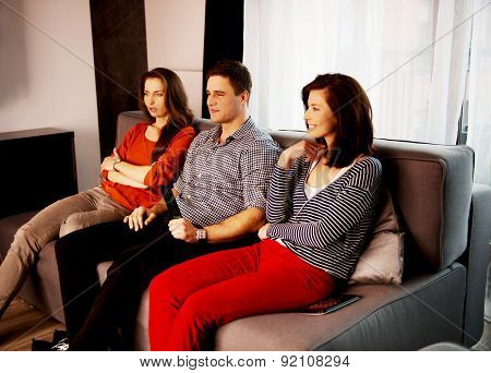 Sisters and brother relaxing at home on the sofa.