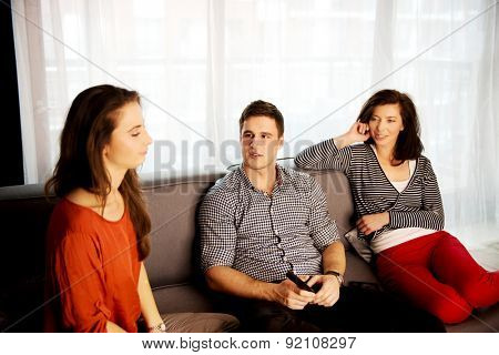 Sisters and brother relaxing at home on the sofa.
