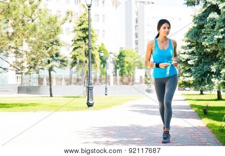 Full length portrait of a young sports woman running outdoors with building on backgruond