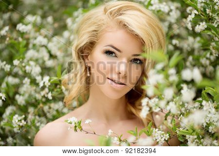 Young spring fashion woman. Trendy girl in the flowering trees in the spring summer garden. Springtime or summertime. Lady in spring landscape background. Allergic to pollen of flowers Spring allergy
