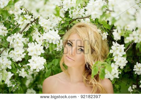 Young spring fashion woman. Trendy girl in the flowering trees in the spring summer garden. Springtime or summertime. Lady in spring landscape background. Allergic to pollen of flowers. Spring allergy