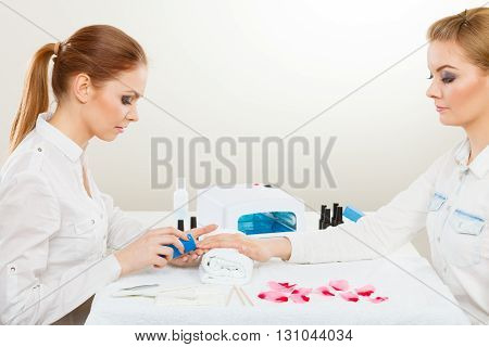 Relaxing time and wellness day concept. Blonde elegant woman visiting professional manicurist salon. Beautician makes perfect nails to client.