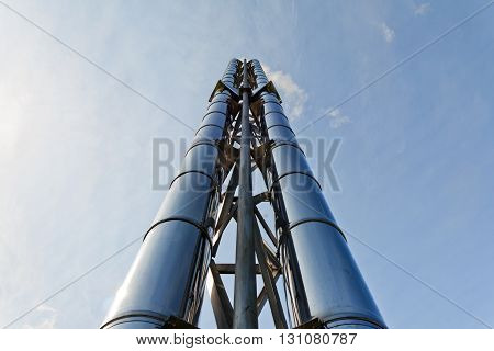 Two (2) new shiny smokestacks rise up into the blue sky. Of metal pipe (steel)