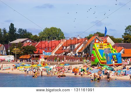 HEL, POLAND - AUGUST 10, 2015: Sandy beach scene of many people suntanning, relaxing and enjoying the shore in summer day. Hel is one of most famous cruise travel destinations in Poland.
