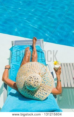 Pretty blond woman  enjoying a cocktail at the  swimming pool