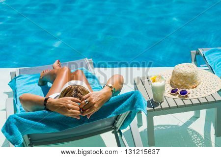 Pretty blond woman  enjoying a cocktail at the  swimming pool