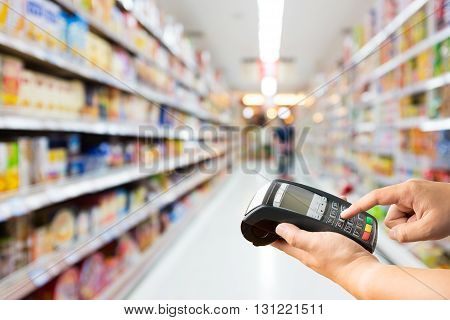 Hand hold credit card machine on supermarket store blur background with bokeh