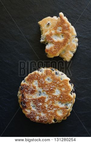 Welsh cakes a traditional griddle cake made with flour and dried fruit on a slate background