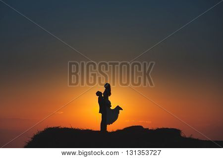 Silhouette of a loving couple on the background of the setting sun, mountains, islands and sea. Santorini. Greece. Just married. Walk. Walk at sunset. Walk through the mountains at sunset.
