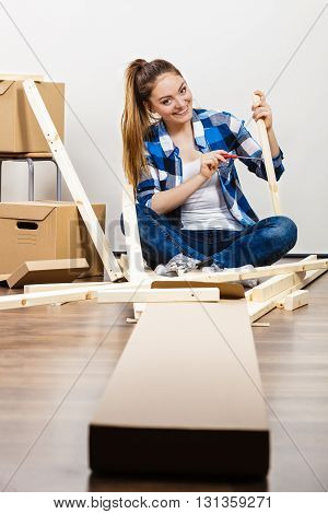 Woman Moving Into Apartment Assembly Furniture.